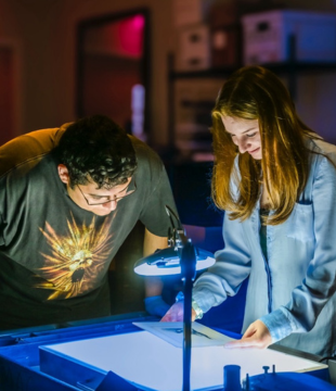 JMU students examine the condition of a print by Rembrandt in the Madison Art Collection.