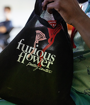 A person holding a bag that has the Furious Flower Poetry Center logo printed on it.