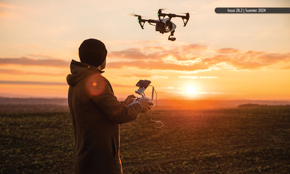 A man files a drone as the sun sets.