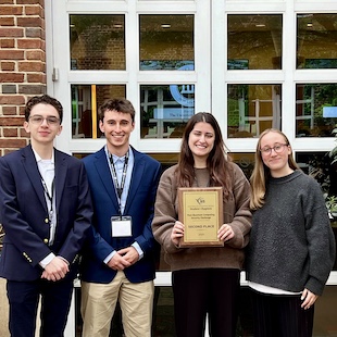 (L-R): Andres Parra van-Arcken, Matthew McGowan, Alexis Jhonson, and Nicole Jhonson holding a plaque.