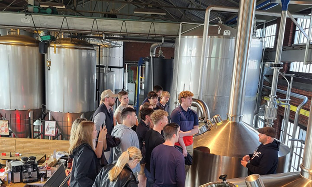 Students listen to a tour guide at a brewery.