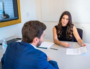 A man and a women sit across the table from each other during a sales competition.