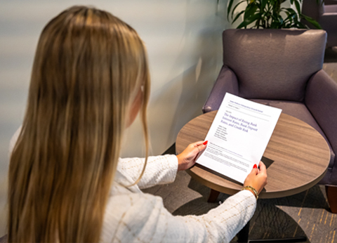 A young women holds a printed research article. 