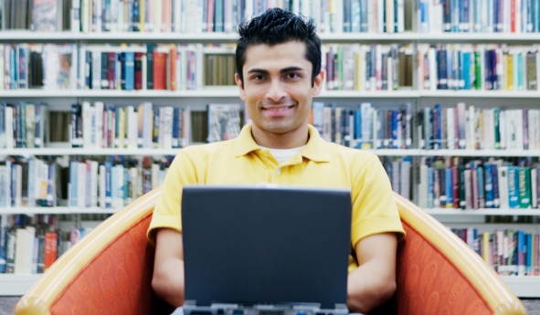 Student in a library with a laptop