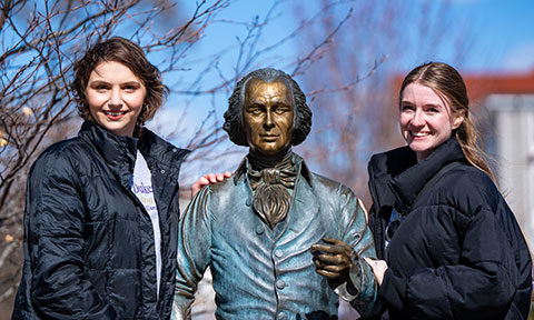 Two people standing on campus with the Jimmy statue