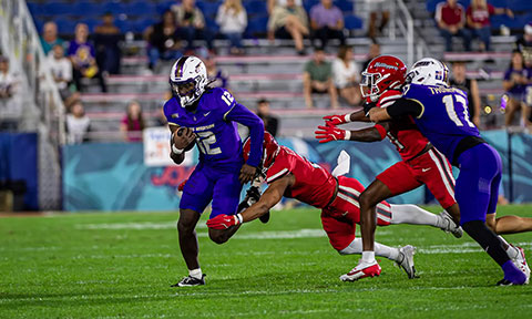 A JMU football player runs the ball.