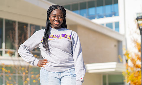 Student standing outside a residence hall smiling