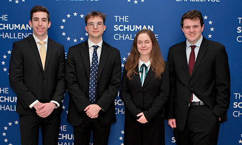 Students in business attire posing in front of a backdrop that says The Schuman Challenge