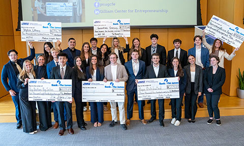 Students in business attire posing with large donation checks