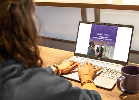 A person working on a laptop viewing a presentation about a Leadership Instruments Library.