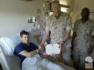 chapman in hospital bed receiving award from officers