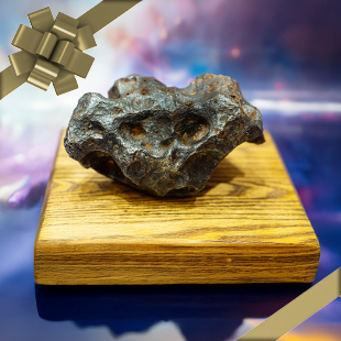 A meteorite displayed on a wooden base with a festive ribbon overlay.