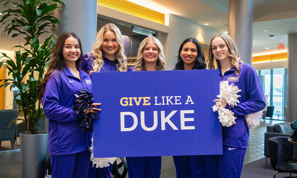 Dukettes keeps a sign with reading "Give like a duke" During the promotion of the school spirit.