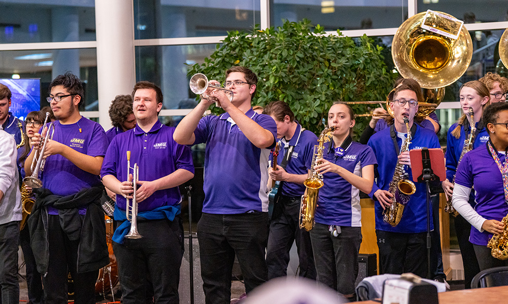 The MRDS N Purpur shirts play brass and wood -based instruments at a lively event.