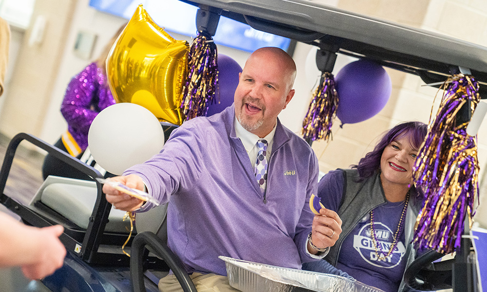 Tim Miller distributes JMU Day Cookies from a golf car in Urec.