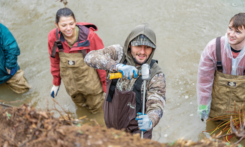 Professor Carole Nash’s ISAT students plant trees at the JMU Farm along a stream bank as part of their capstone project.