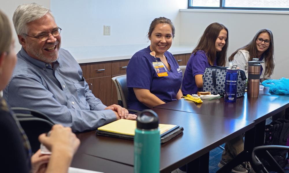 Female nursing student sits at a table with health care professionals