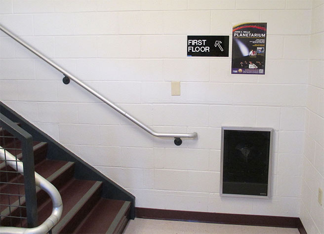 Planetarium poster is on the wall to the right of the stairs visitors need to use.