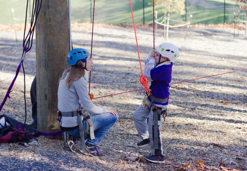 worker talking with child before going on challenge course