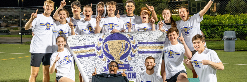 students posing with championship banner after winning intramural sport league