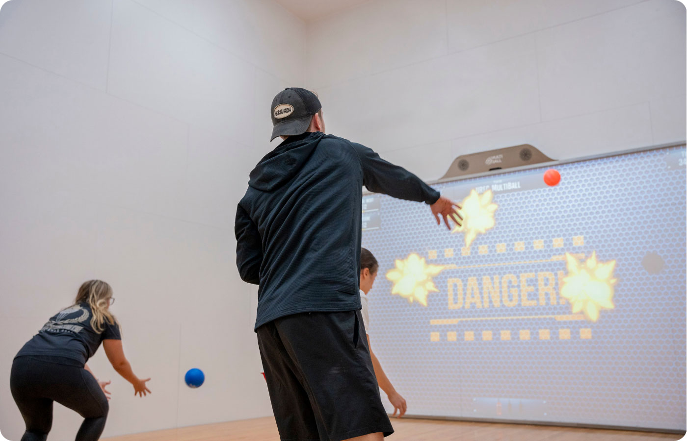 students throwing a ball at an interactive game wall