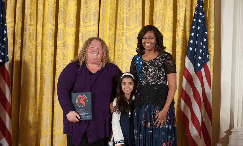 Kim Hartzler-Weakley and Sarah Hussein pose with then-First Lady Michelle Obama at a White House ceremony recognizing the Gus Bus.