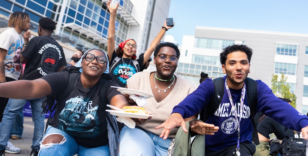 A group of young adults enjoying a lively outdoor event, sharing food and celebrating together.