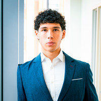 DeAngelo Smith in a tailored blue suit standing confidently in a modern indoor setting.