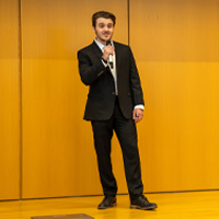 Jacob McMurdy stands on stage in the Forum.