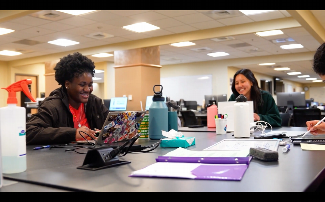 A group of two people working on their laptops and smiling  with a video hyperlinked