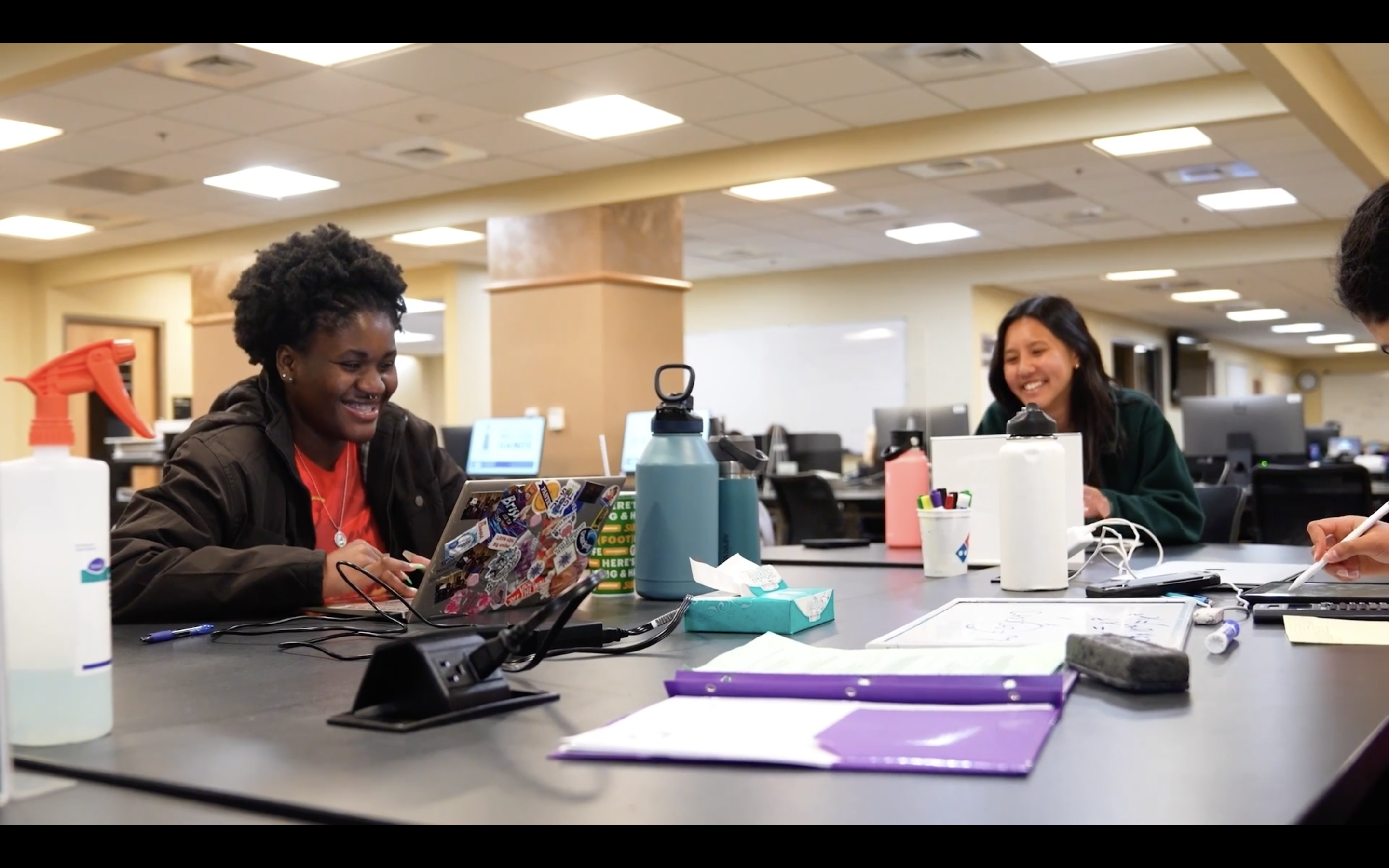 A group of two people working on their laptops and smiling  with a video hyperlinked