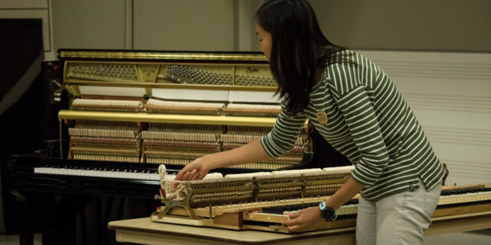 Piano technician showing inside board of piano