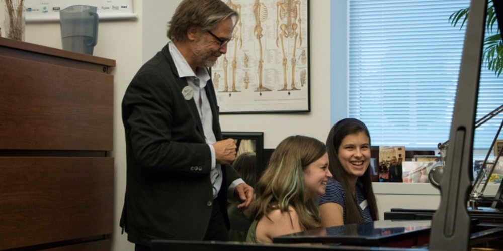 Piano professor working with two piano students at piano