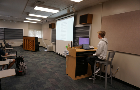 Student showing their composition on a laptop and projector