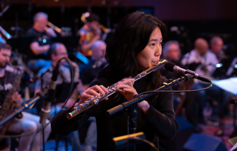 Woman performs on a flute with a jazz ensemble