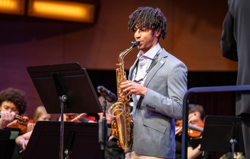 Man performs saxophone with orchestra