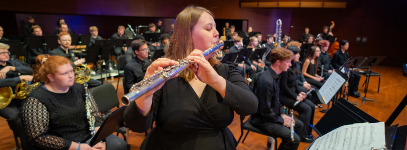 woman playing flute in front of wind ensemble