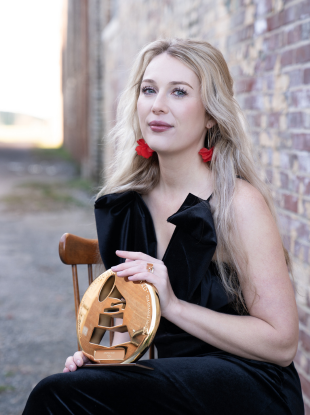 Woman sitting in chair holding grammy award