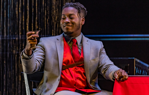 man holding a drink in an opera scene