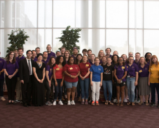 group of people standing in a lobby smiling at camera