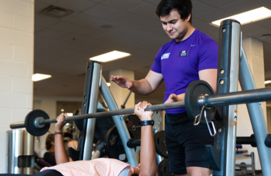 student weight lifting with student spotter