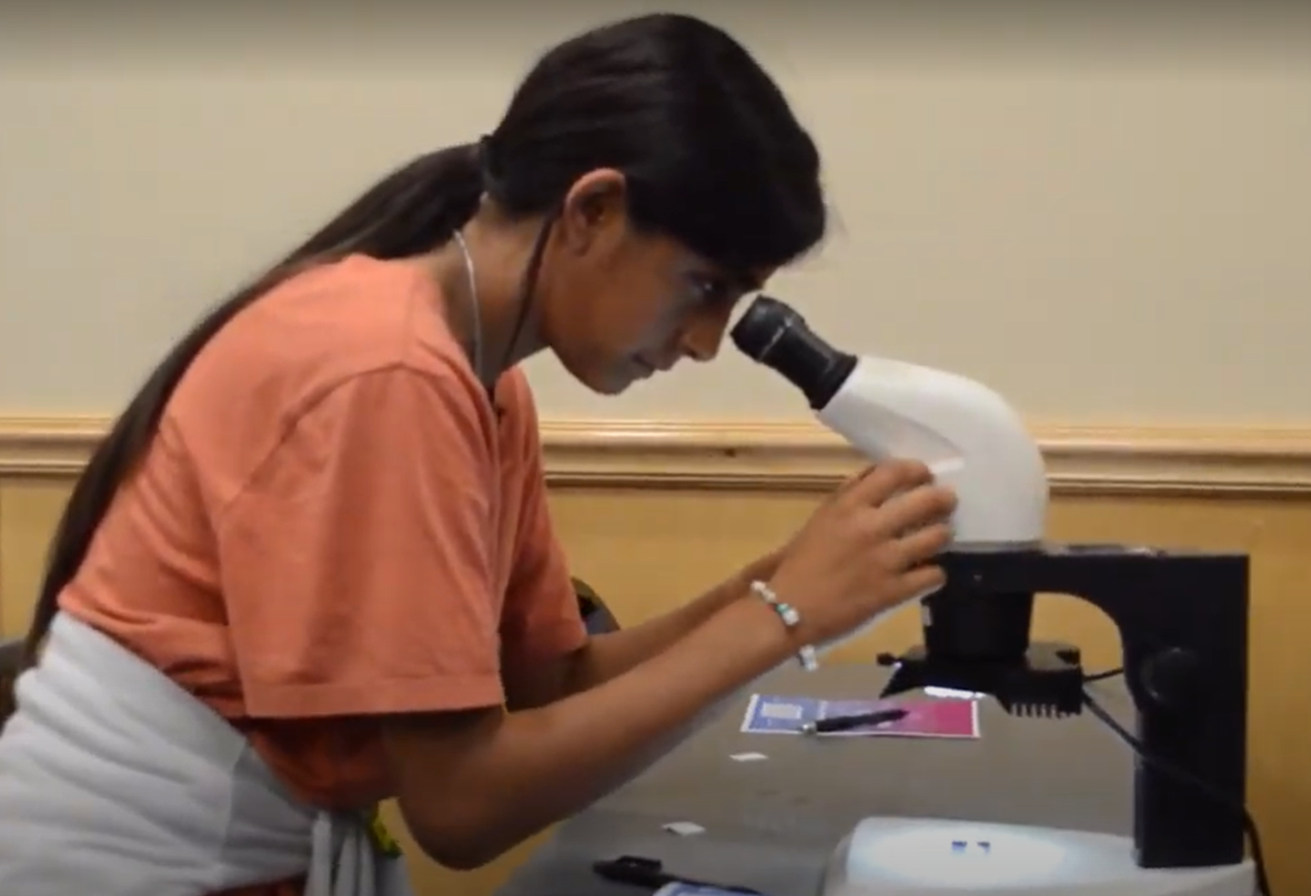 girl looking through microscope