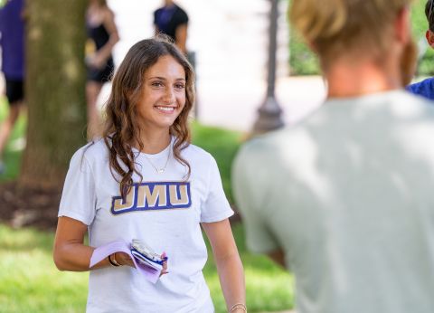 Student wearing a white shirt smiling with a group.