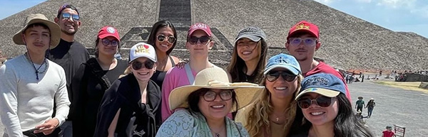 students and a professor pose in front of a temple