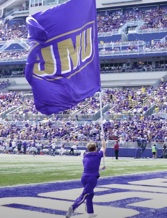 JMU Cheerleader waving JMU flag during football game