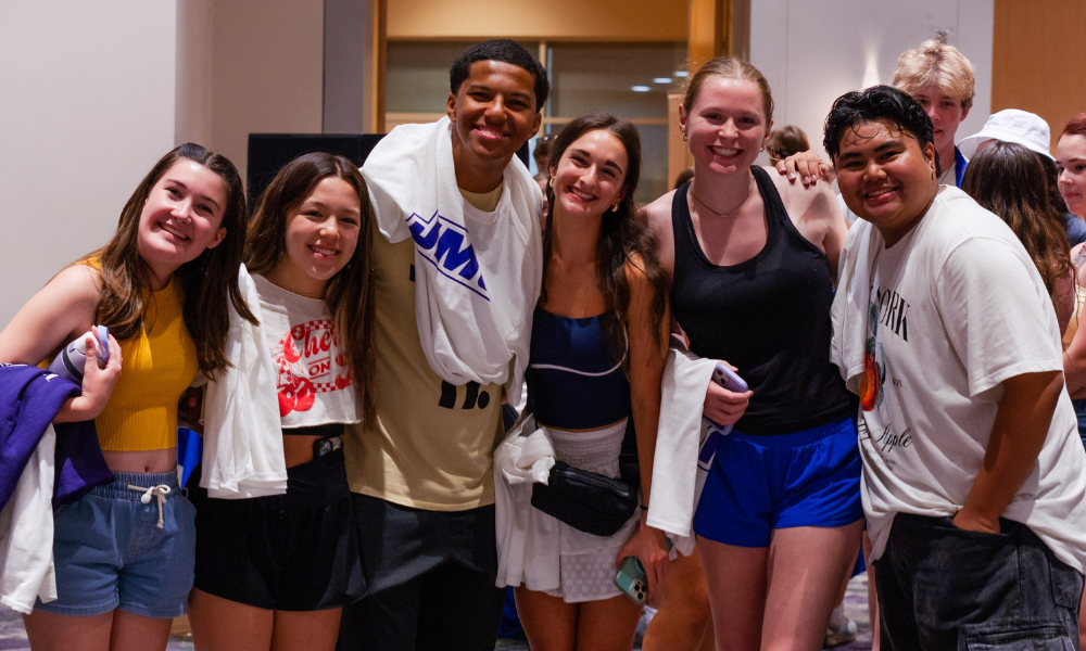 A group of students smiling and posing for a picture at a weeks of welcome event inside of festival