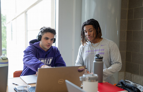 JMU students studying and looking at a computer screen together.