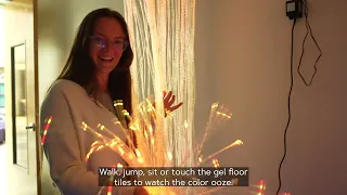 A female college student playing with fiber optic lights in a dark interior room. 