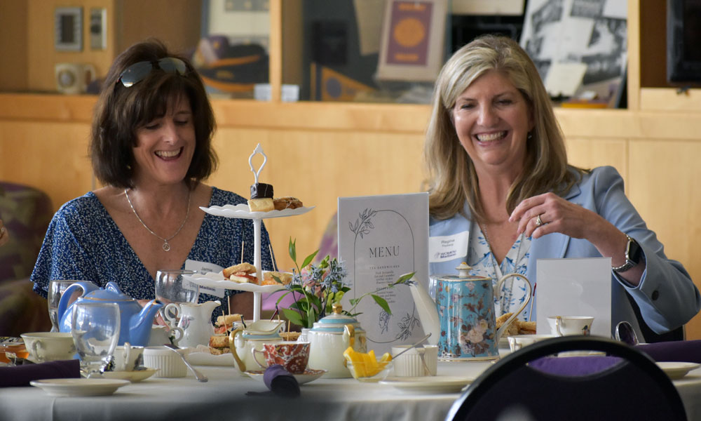 two smiling women at a table set for a tea party