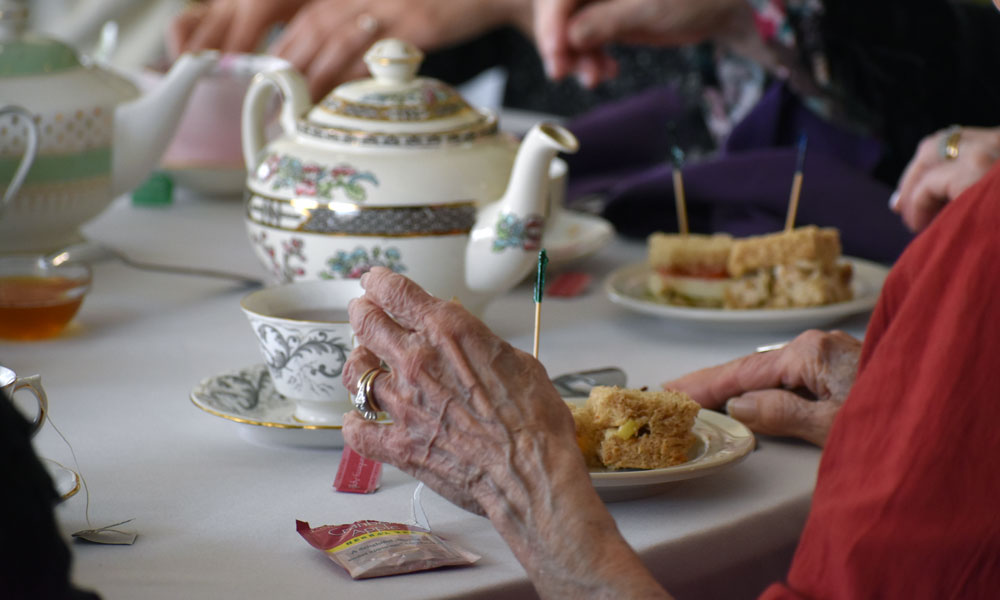 table set for a tea party with elderly hands in foreground